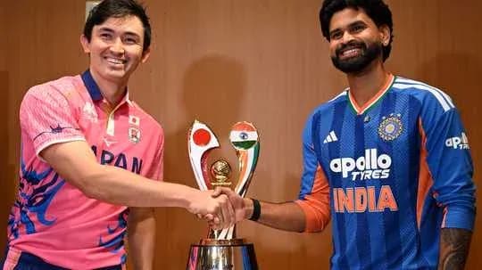 Players from Japan and India shaking hands beside trophy