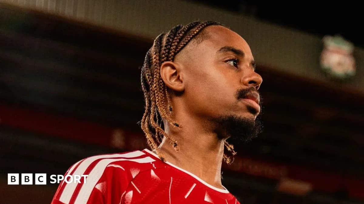 Player in red jersey at stadium, side profile