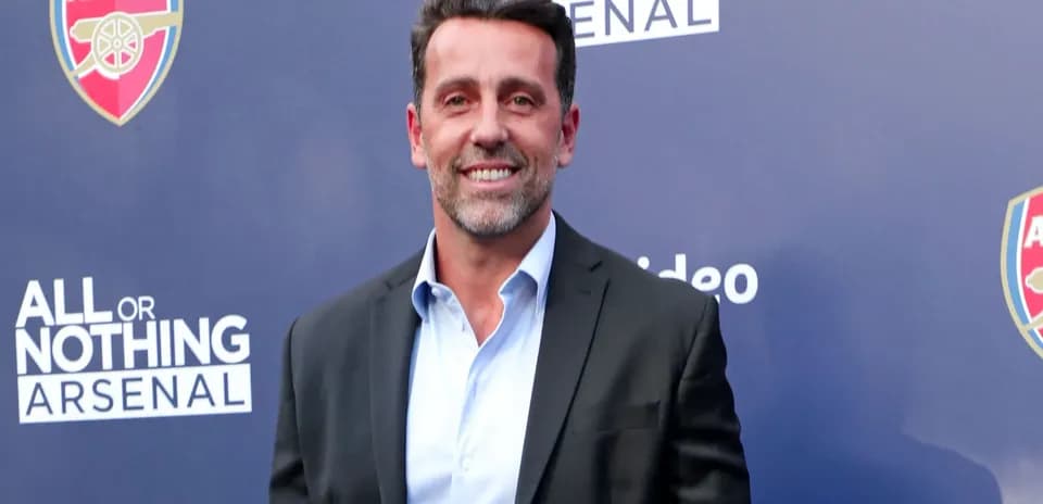 Man in suit smiling at event backdrop