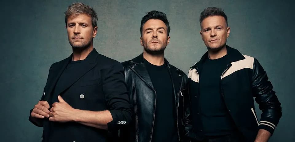 Three male singers posing against a neutral background