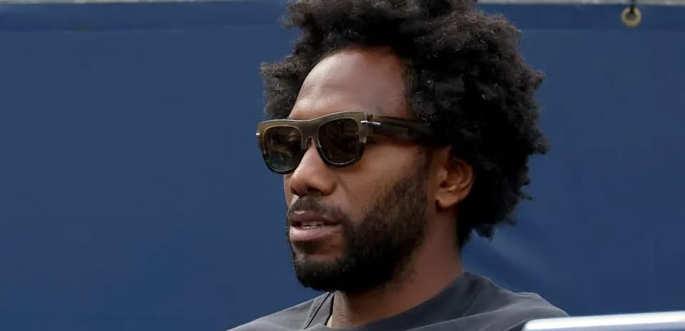 Man with sunglasses sitting at sporting event