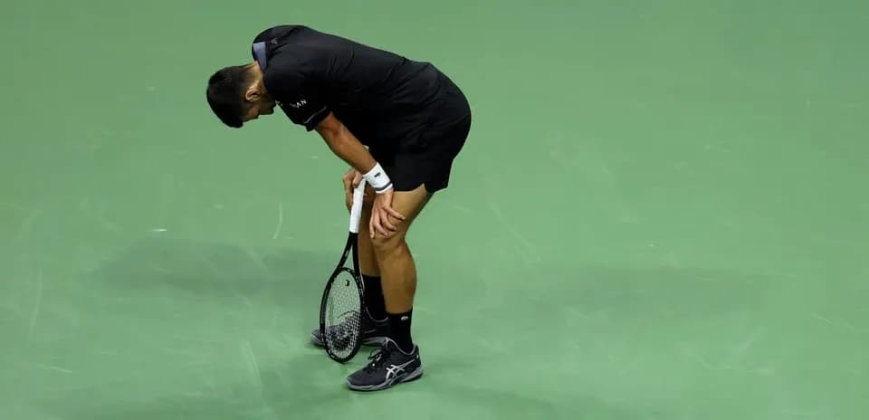 Tennis player bending over on court during match