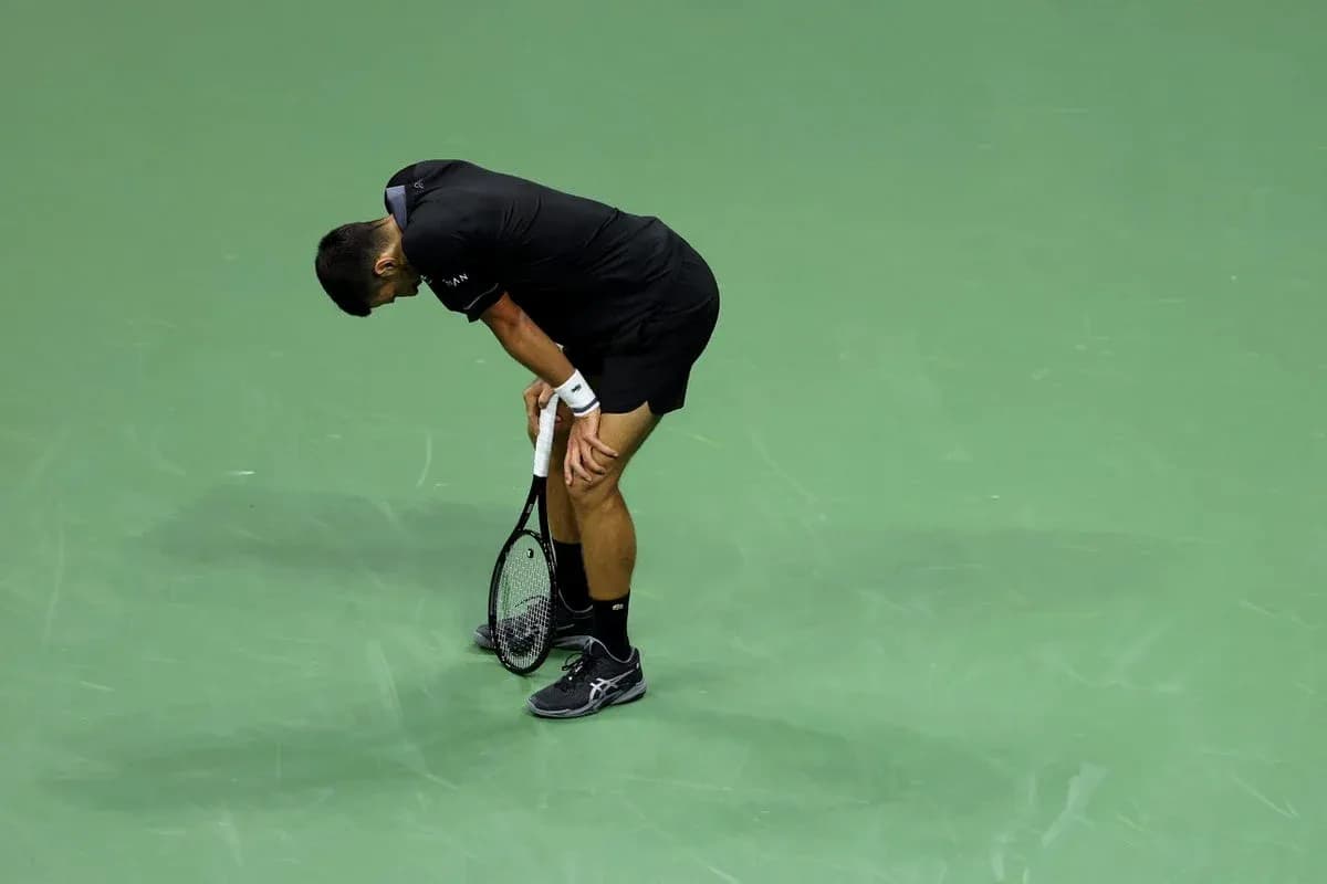 Tennis player bending over on court during match