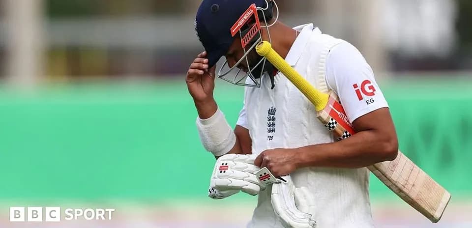 Cricketer walking off field with bat and gloves