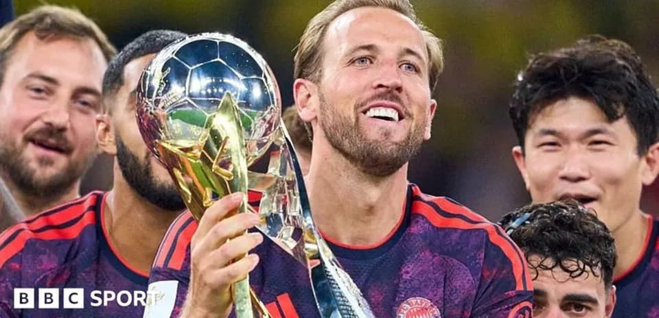 Player holding trophy with teammates celebrating behind