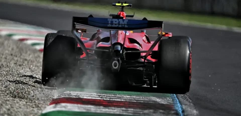 Red Formula 1 car driving on track with dust