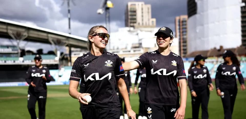 Two cricketers smiling while walking off the field