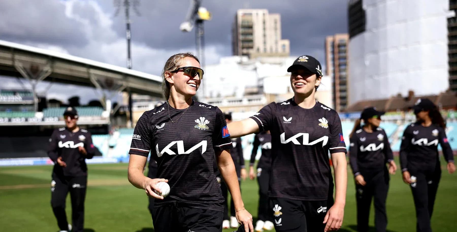 Two cricketers smiling while walking off the field
