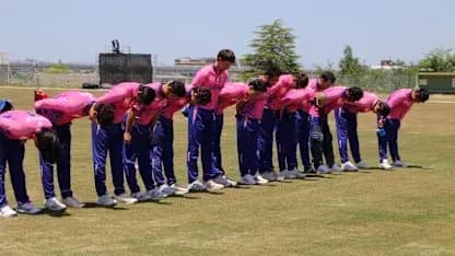 Cricket team bowing in unison on training field