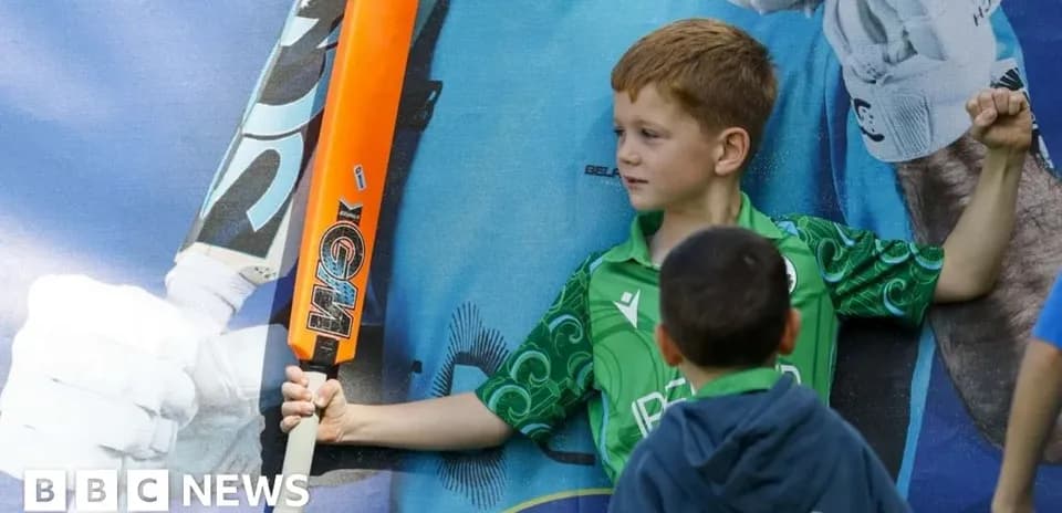 Child posing with cricket bat in front of poster