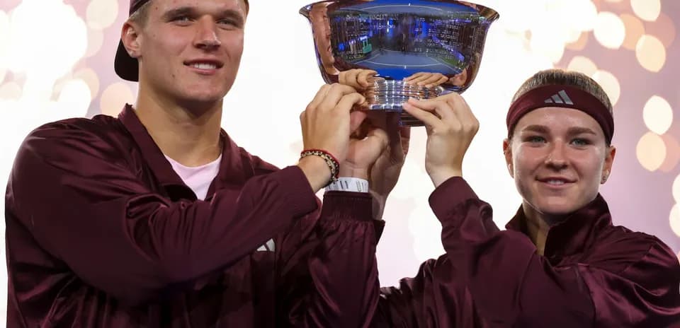 Two players holding trophy with fireworks in background