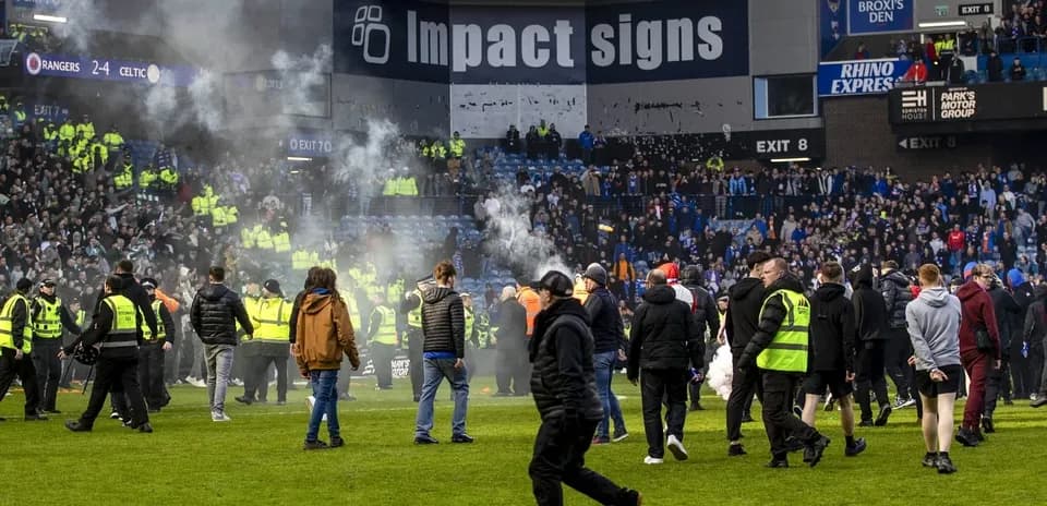 Crowd on pitch with smoke during match aftermath