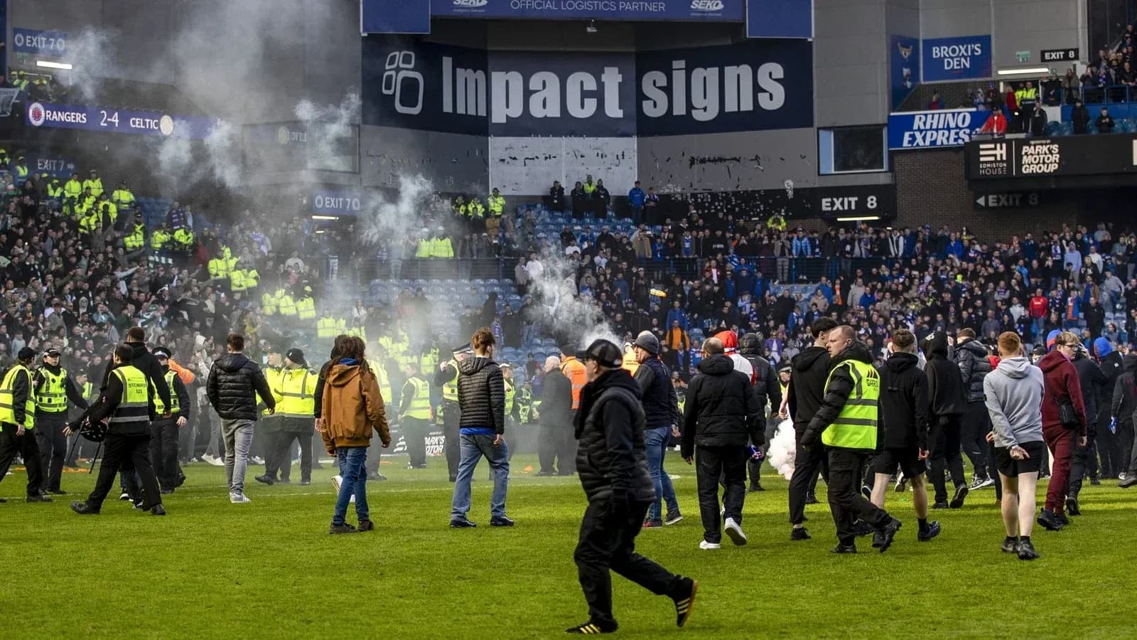 Crowd on pitch with smoke during match aftermath