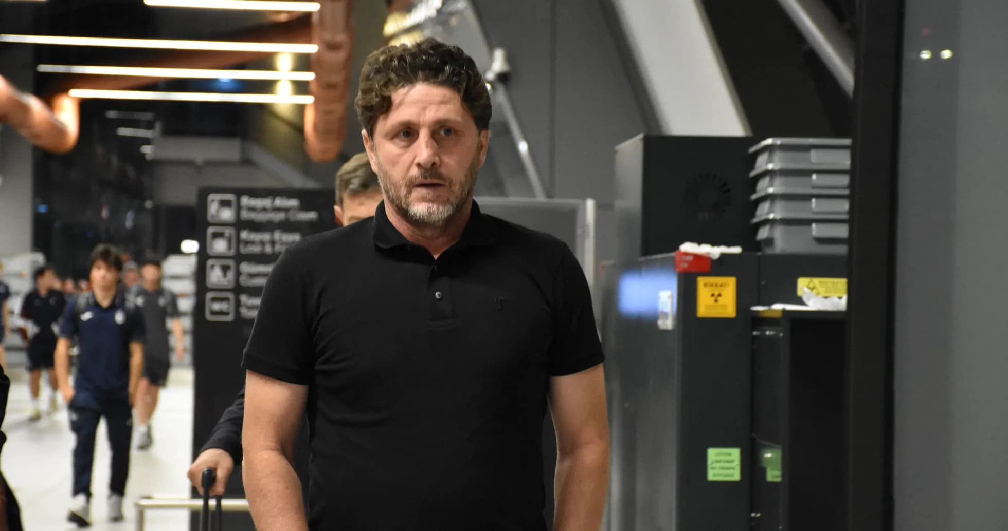 Man walking through airport with team in background