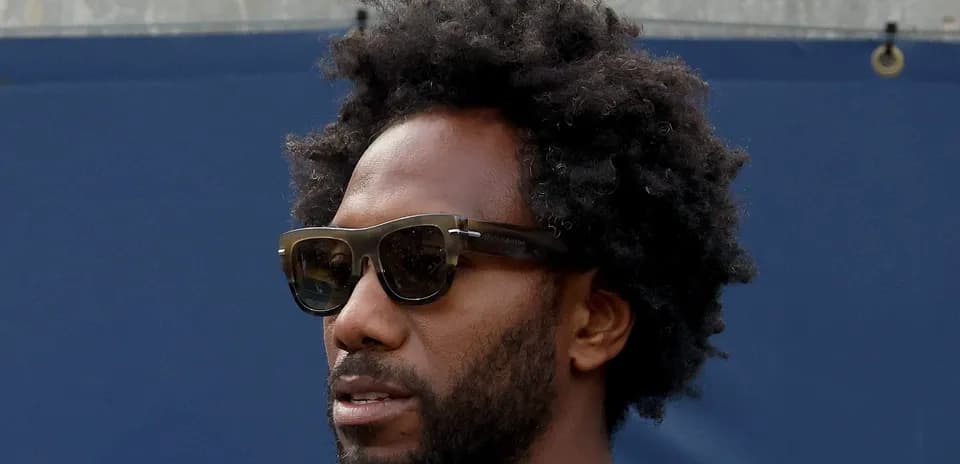 Person wearing sunglasses with curly hair outdoors