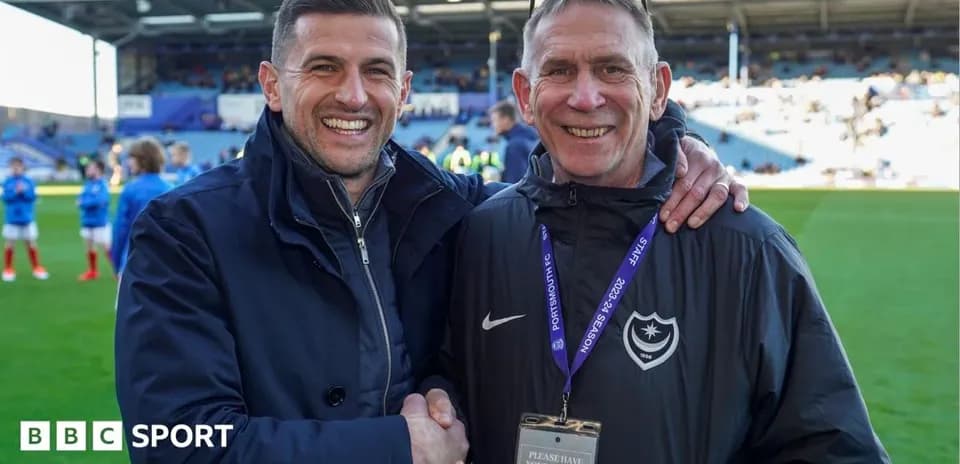 Two men smiling and shaking hands on field