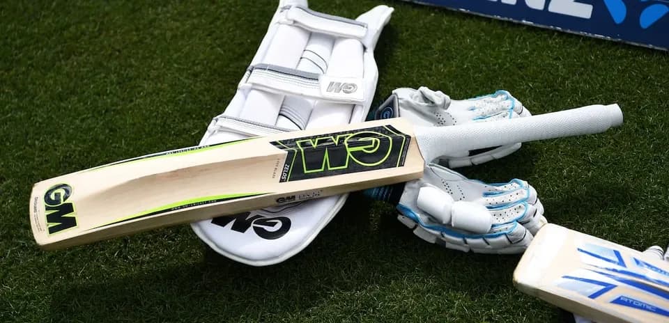 Cricket bat and gloves on the grass
