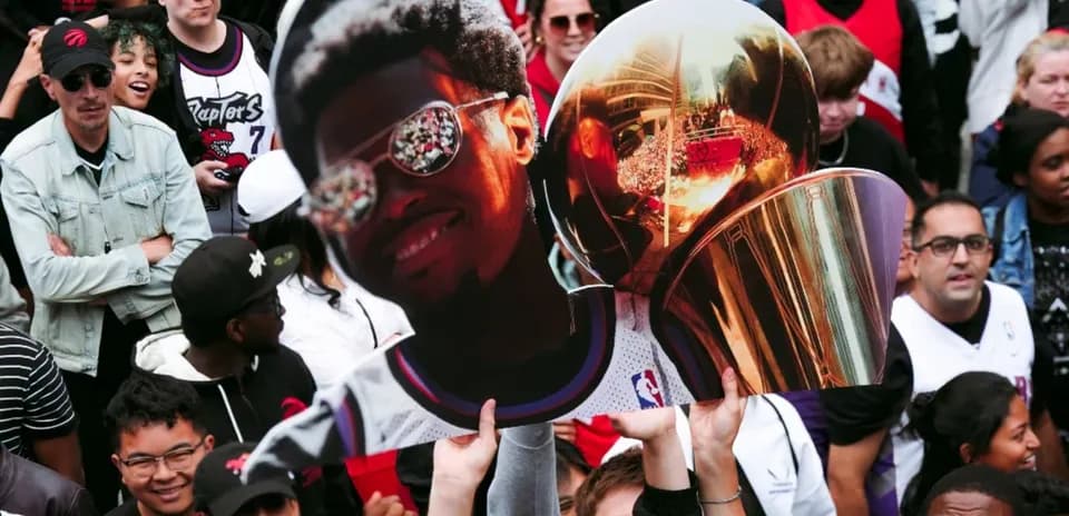 Fans holding giant cutout of player with trophy