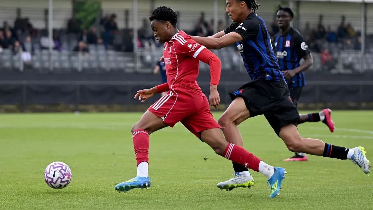 Player in red dribbling past opponent in black Player in red dribbling past opponent in black