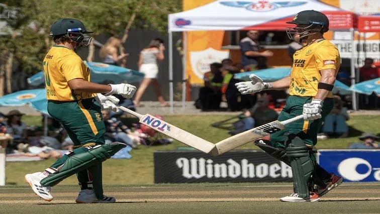 Two cricketers celebrating with their bats on field Two cricketers celebrating with their bats on field