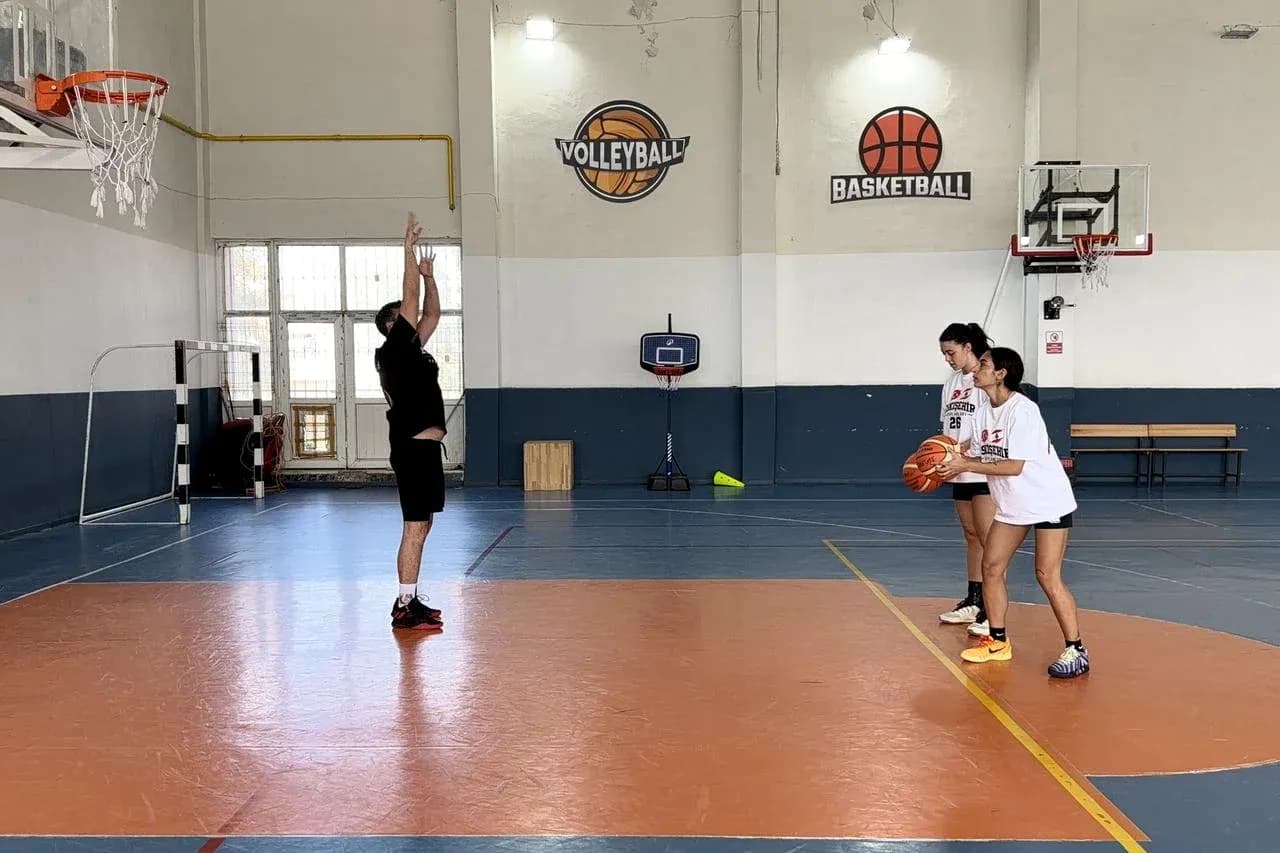 Player practicing shooting while two teammates watch Player practicing shooting while two teammates watch