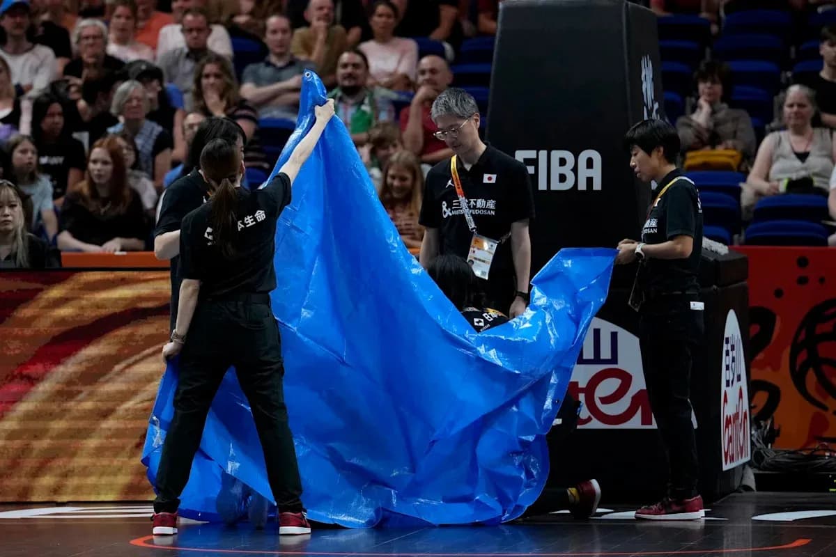 Staff covering court with blue tarp during game Staff covering court with blue tarp during game