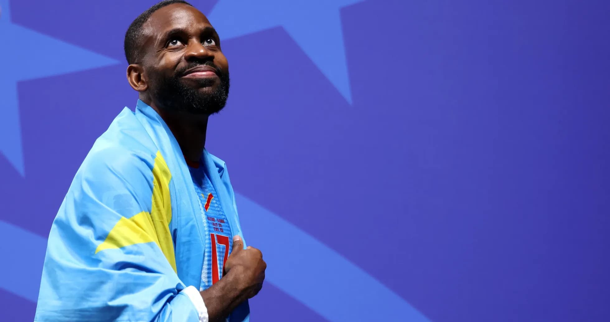 Athlete wearing a flag, looking upwards on stage Athlete wearing a flag, looking upwards on stage