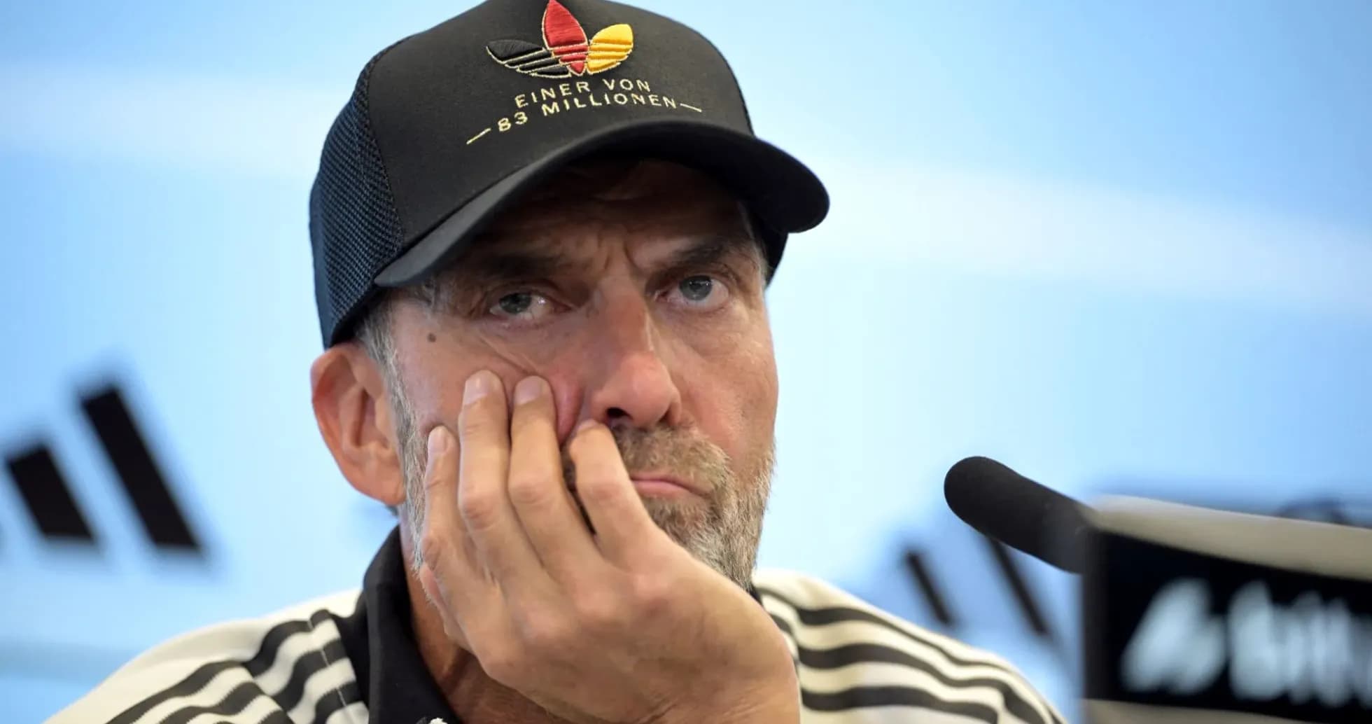 Coach at press conference with hand on face Coach at press conference with hand on face