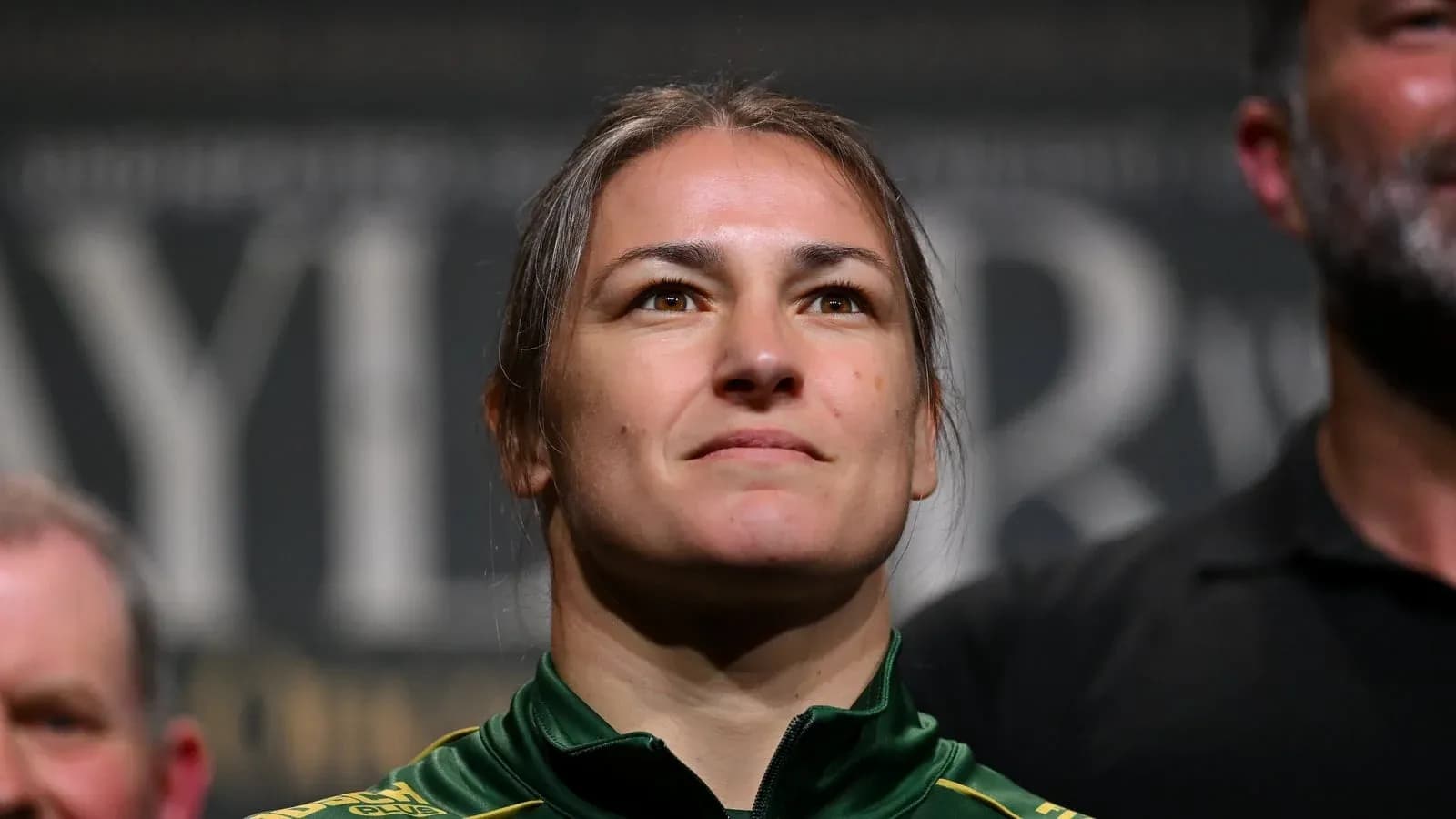 Athlete at a press event, wearing green jacket Athlete at a press event, wearing green jacket