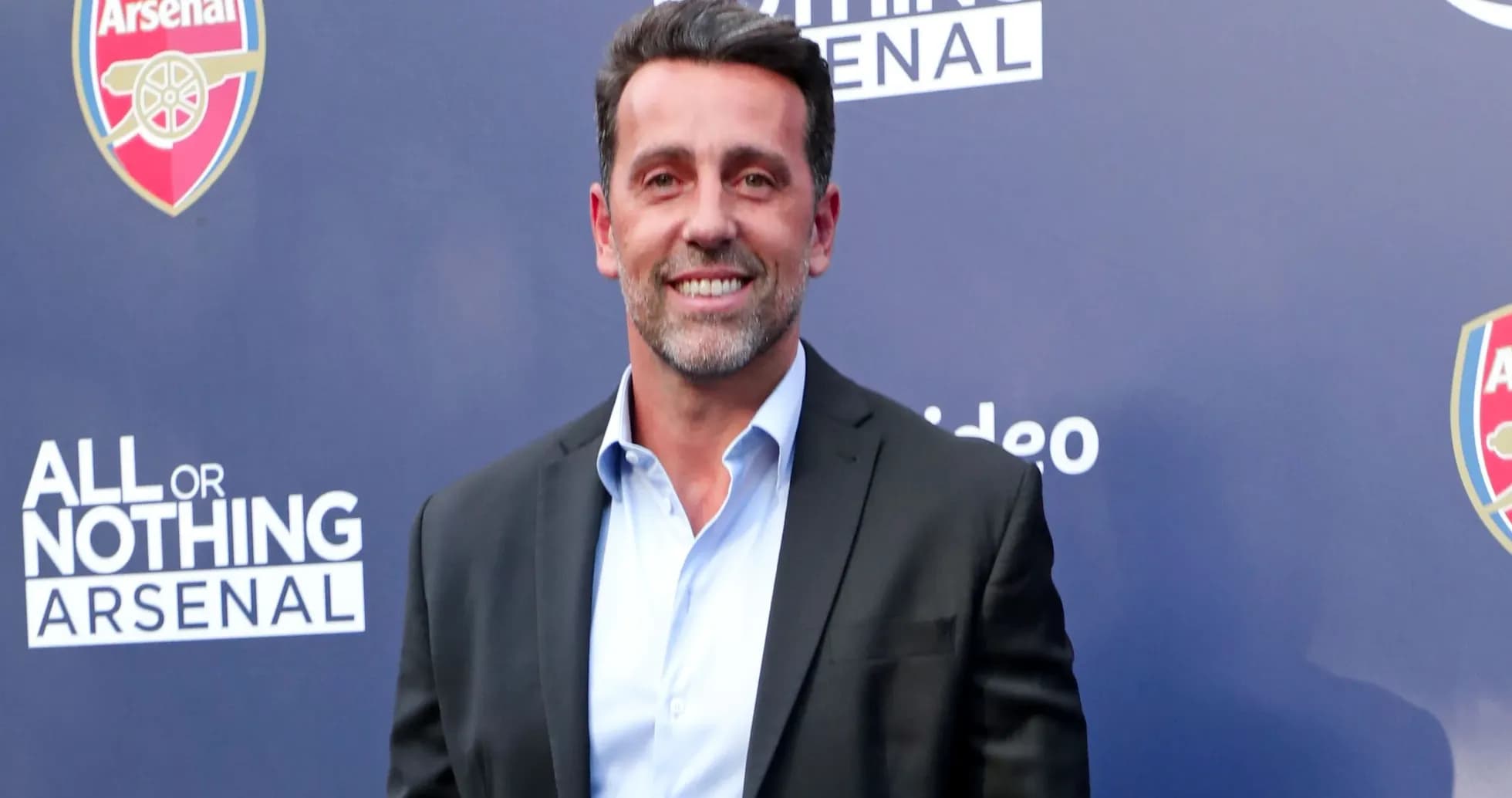 Man in suit smiling at event backdrop Man in suit smiling at event backdrop