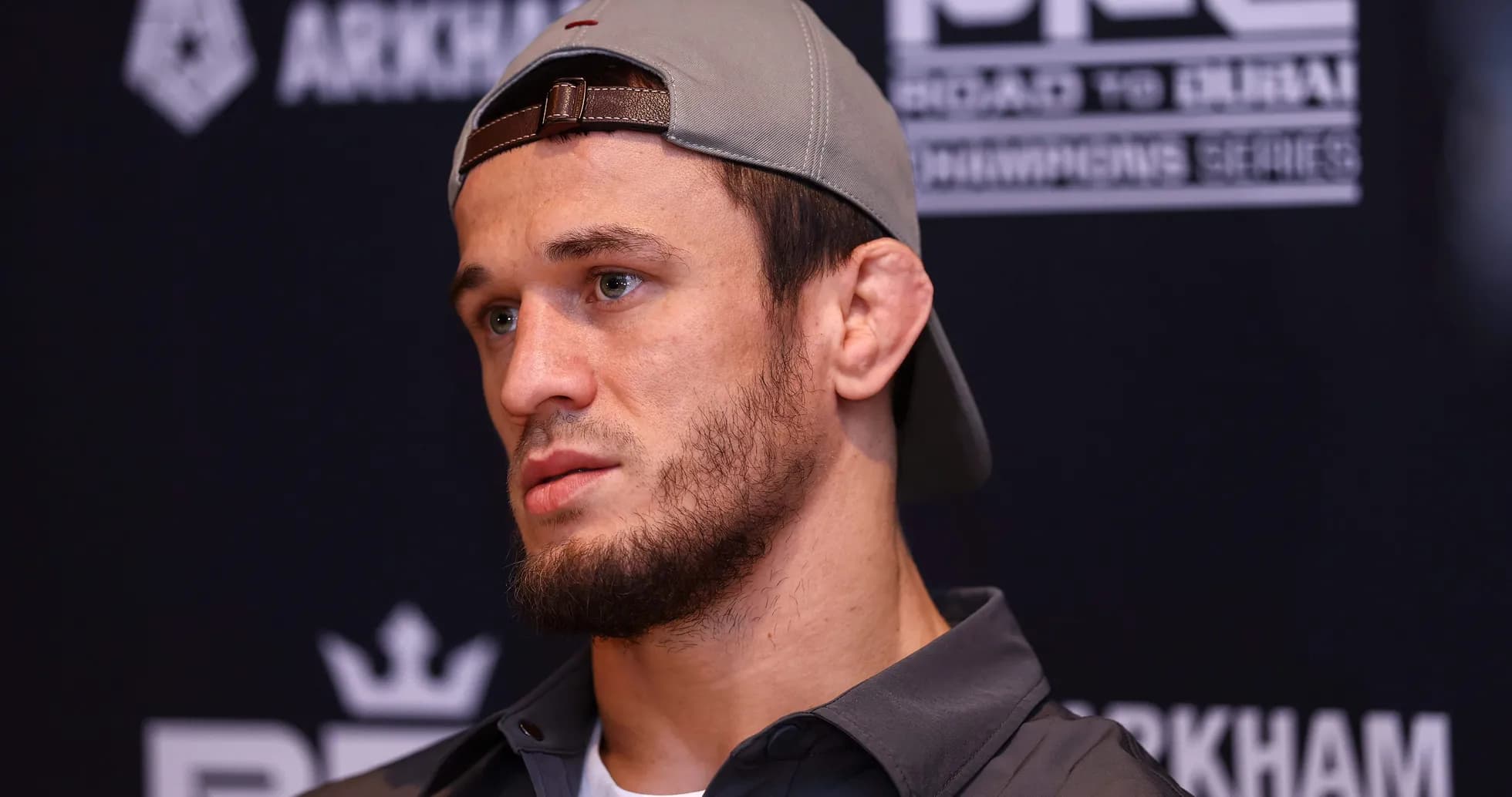 Fighter at press conference wearing cap and serious expression Fighter at press conference wearing cap and serious expression