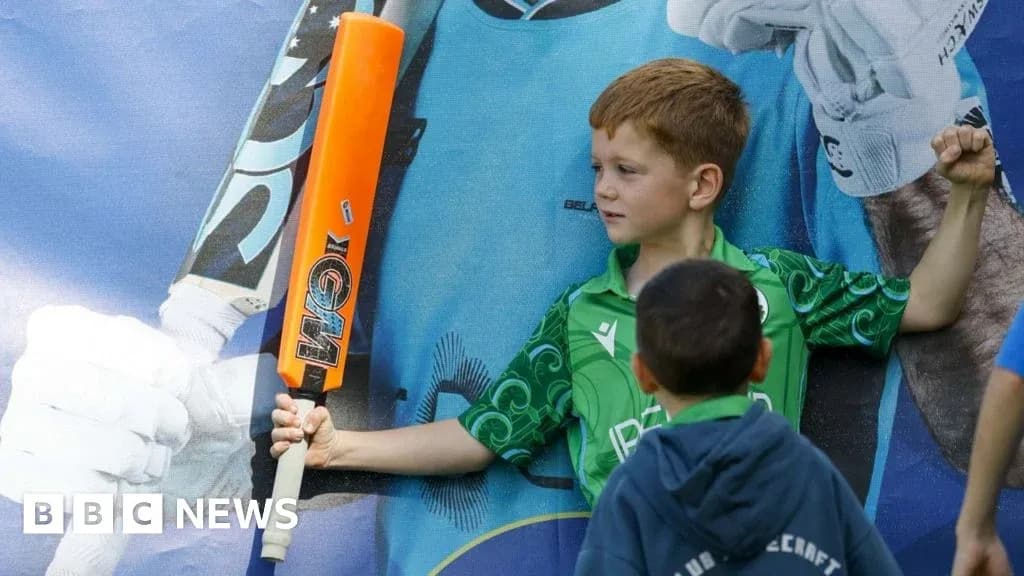 Child posing with cricket bat in front of poster Child posing with cricket bat in front of poster