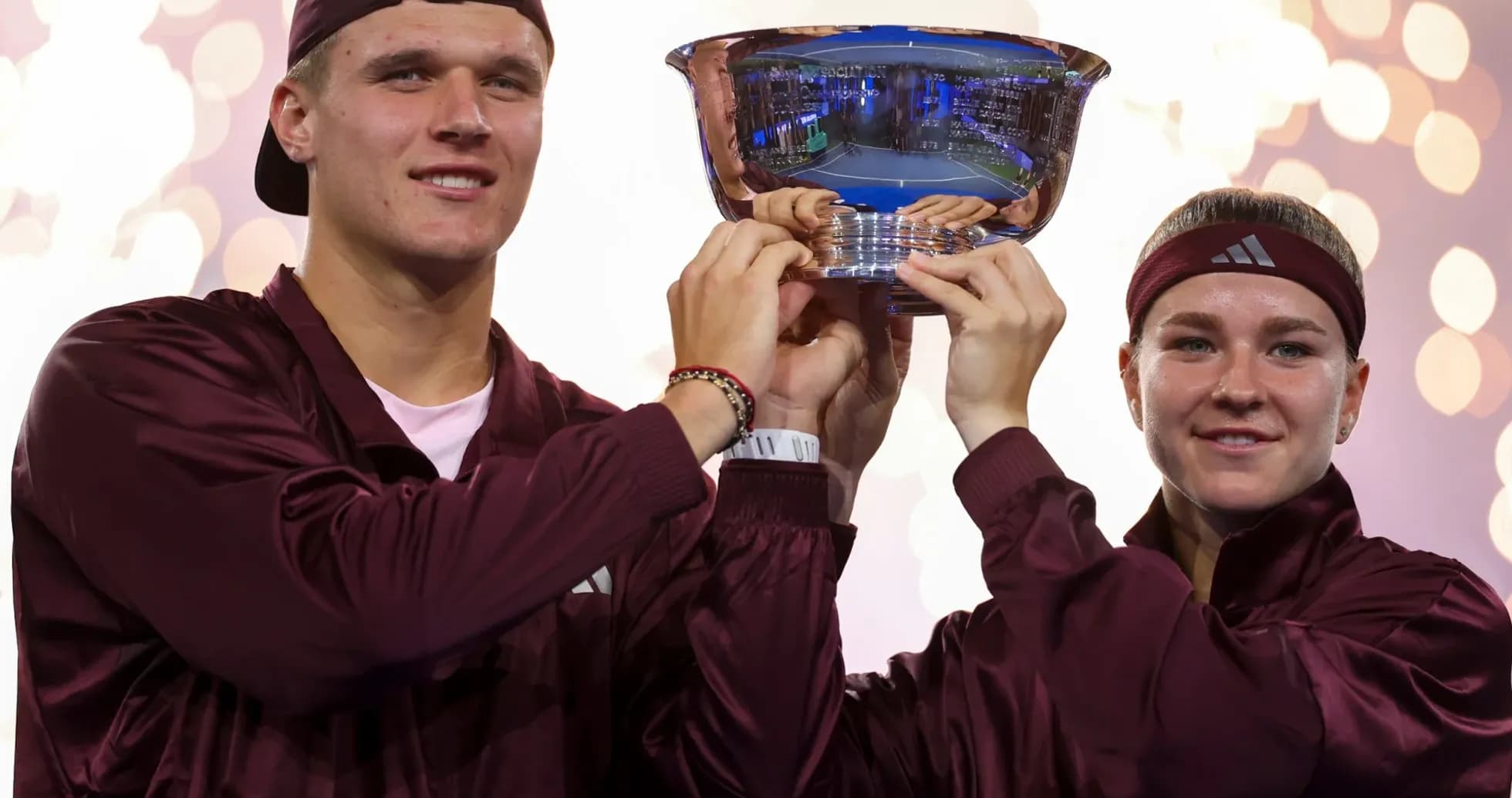 Two players holding trophy with fireworks in background Two players holding trophy with fireworks in background