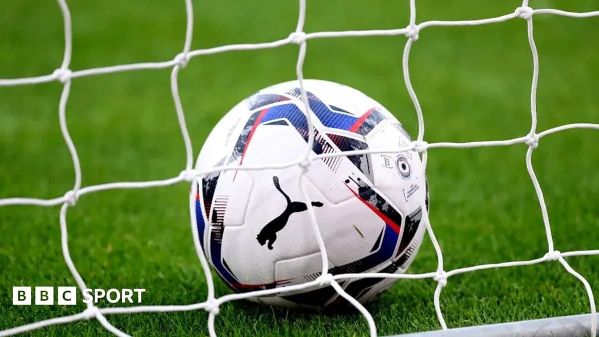 Football in goal net on grassy field Football in goal net on grassy field