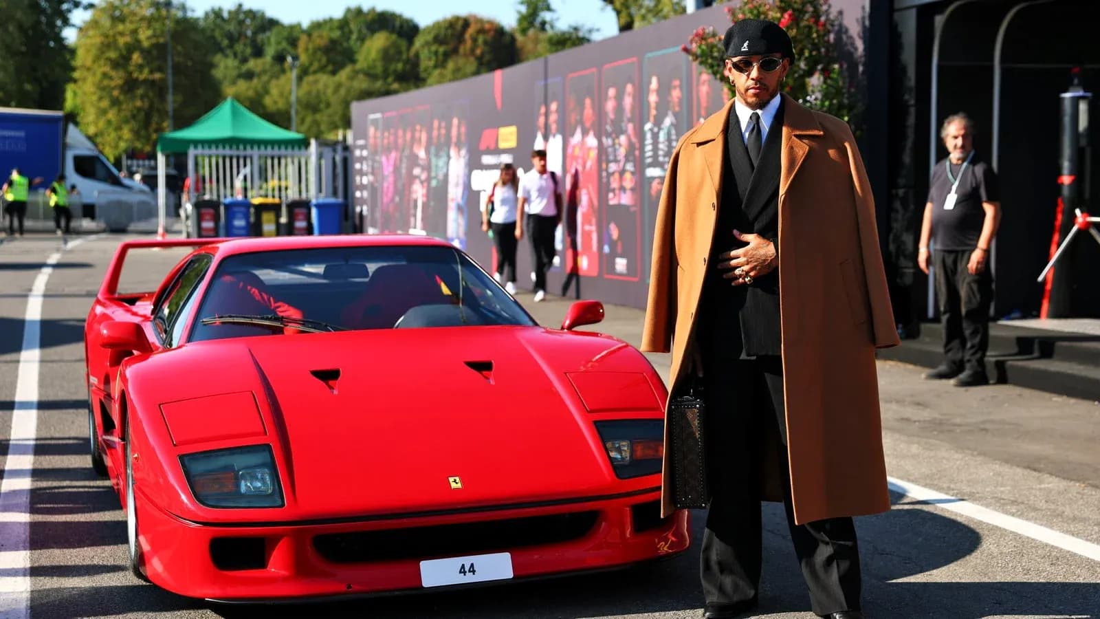Person in stylish attire beside a red Ferrari Person in stylish attire beside a red Ferrari