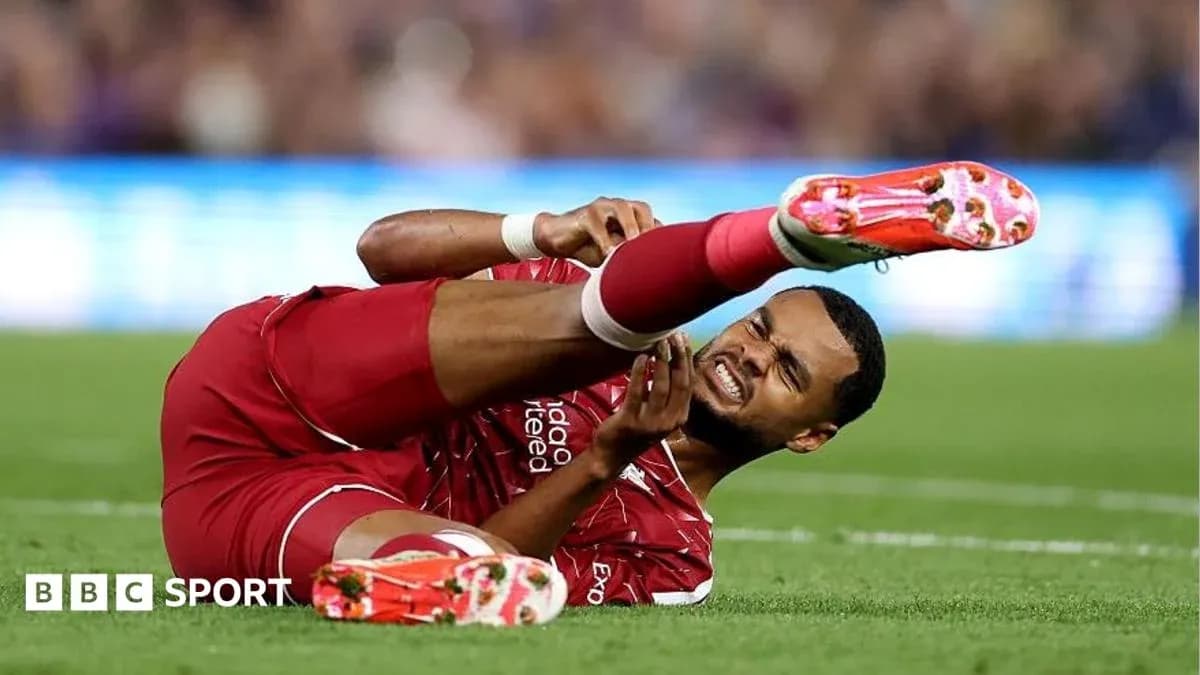 Player in red jersey lying on the field in pain Player in red jersey lying on the field in pain