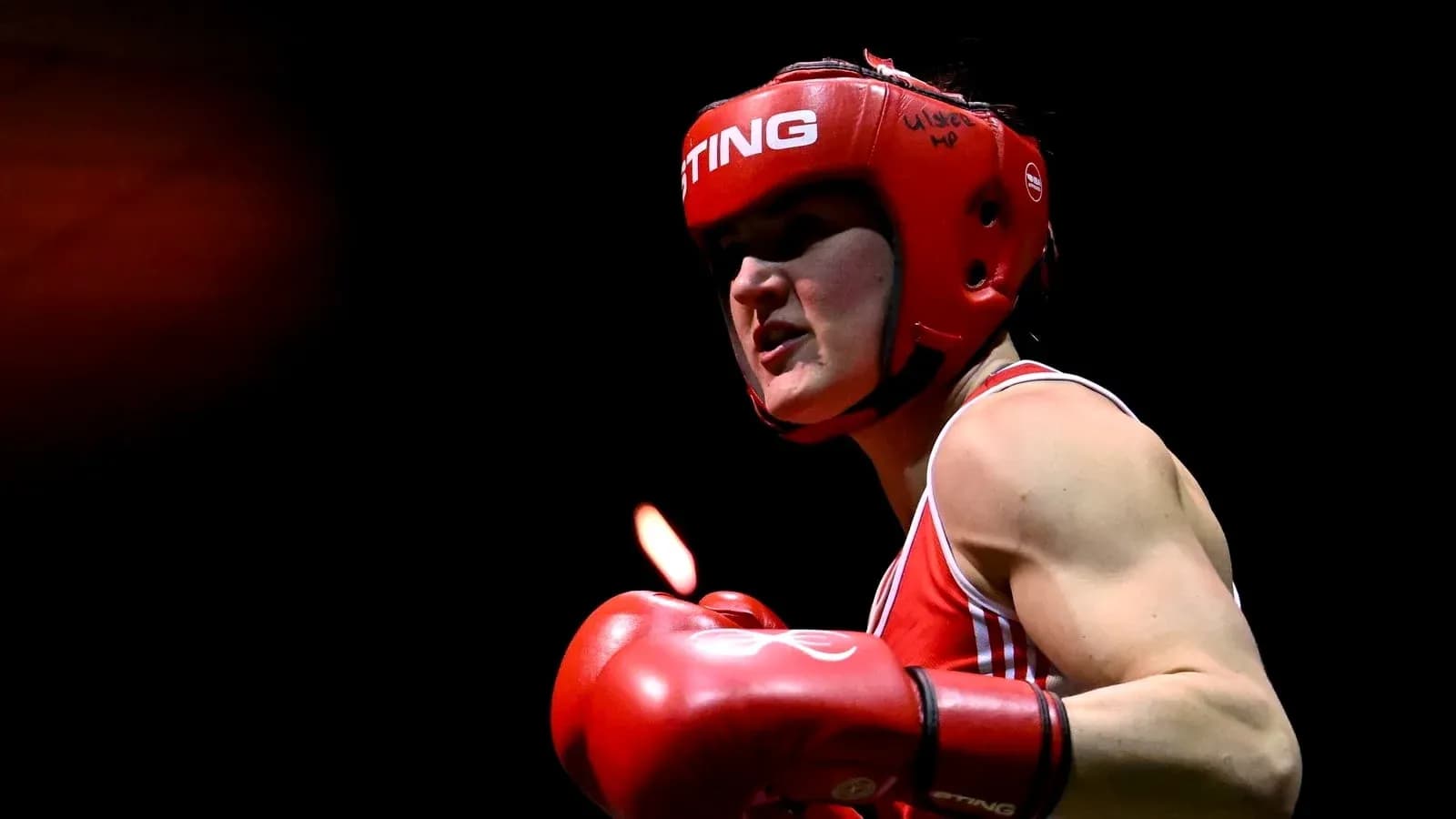 Boxer wearing red gloves and headgear in action Boxer wearing red gloves and headgear in action