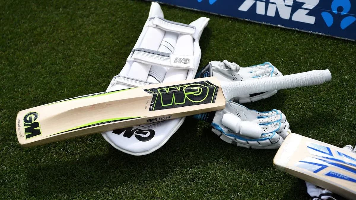 Cricket bat and gloves on the grass Cricket bat and gloves on the grass